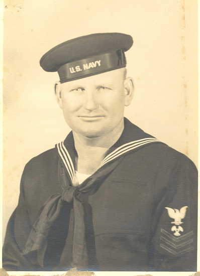 Smiling sailor wearing a dark U.S. Navy uniform and cap.