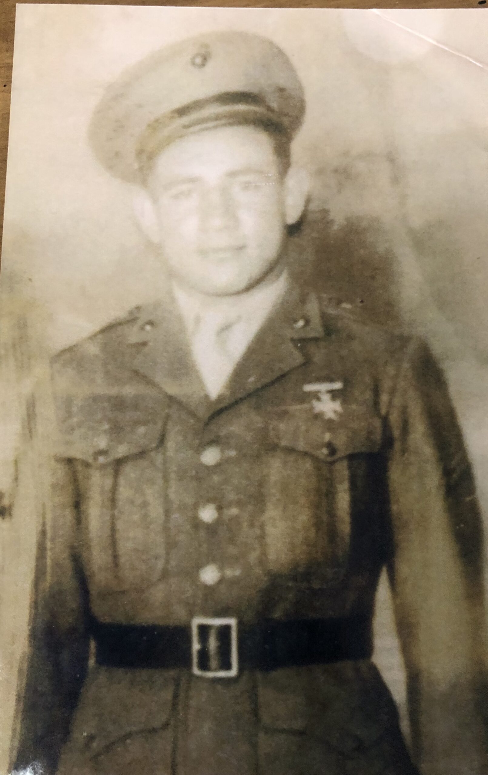 Serviceman wearing a military uniform and cap in a formal portrait.