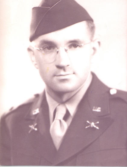 This is an old black and white photo of a man in military uniform, wearing glasses and with a tie. He is looking directly at the camera.