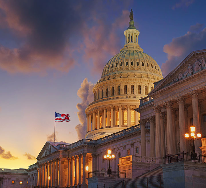 United States Capitol illuminated beneath a cloudy evening sky.