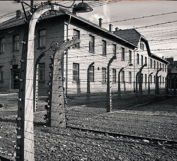Barracks surrounded by barbed-wire fencing at a concentration camp.