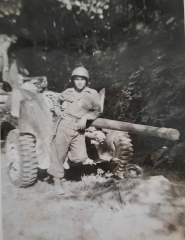 Soldier seated outdoors on a large artillery gun.