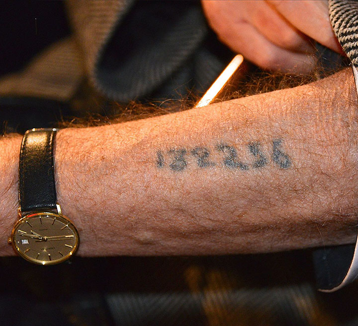 Close-up of a Holocaust survivor’s tattooed identification number on their forearm.