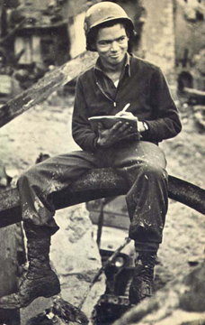 Serviceman seated outdoors while writing in a notebook.
